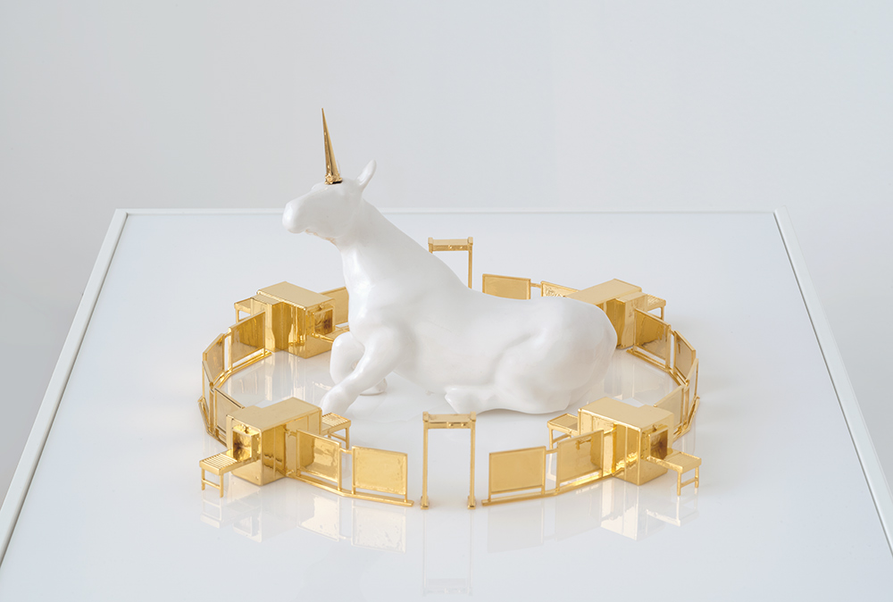 Sculpture showing a ceramic unicorn surrounding by a luxury gold checkpoint.